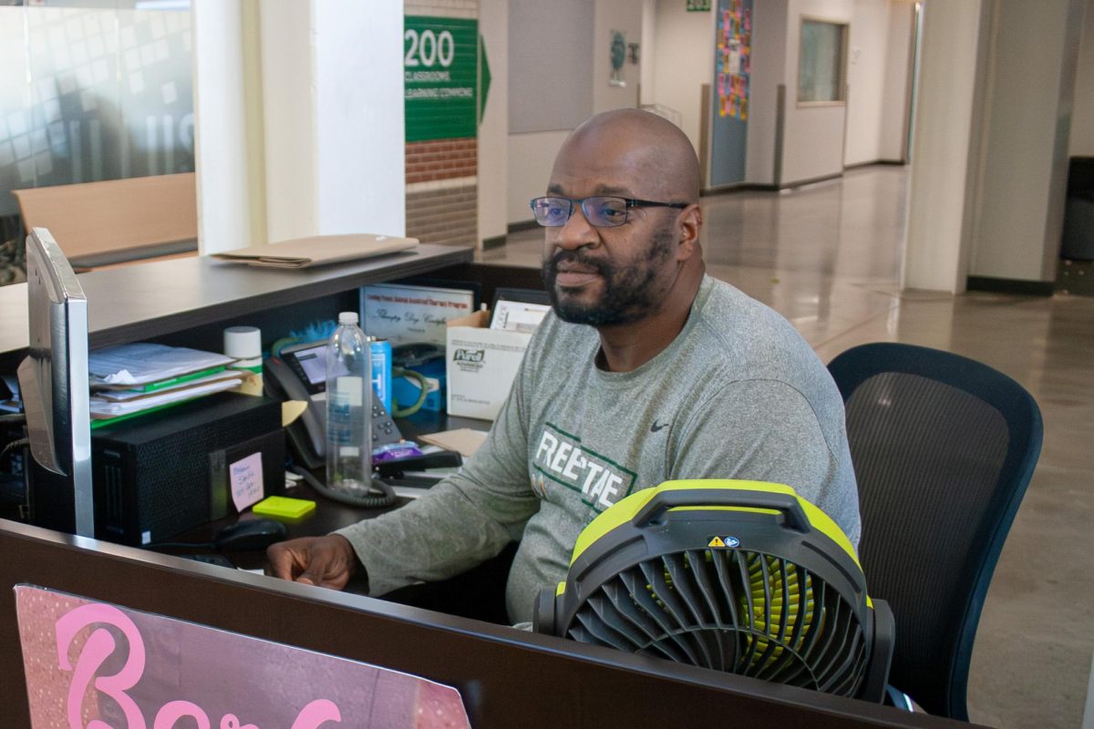 Working at his desk, security guard and Best of Lawrence winner Dee Kemp calls over school support dog Wayne.