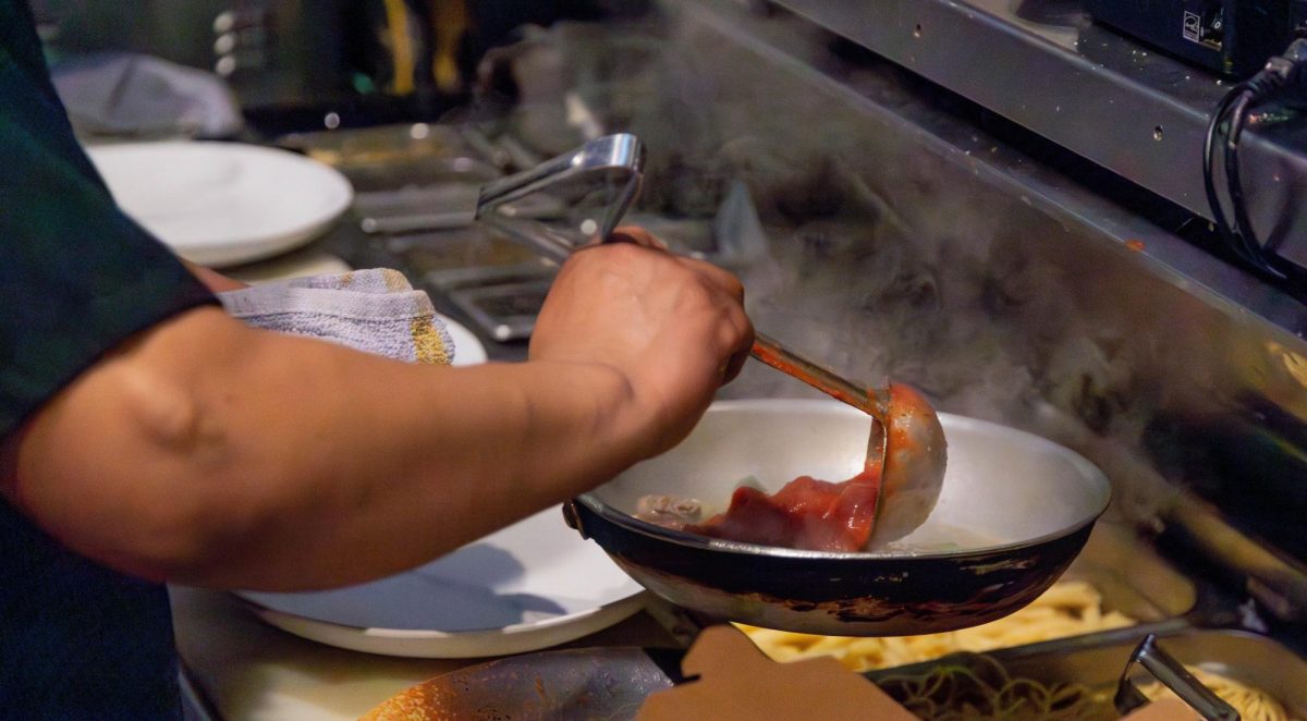 Flipping burgers, Chef Warren from Burgers by Biggs finishes making a menu special, the Jay Hog Burger. 