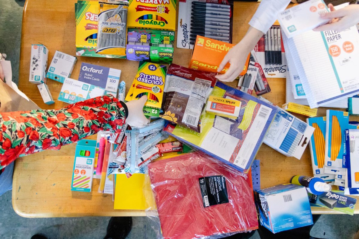 Digging through materials, students organize donations for teachers for the teacher supply drive.