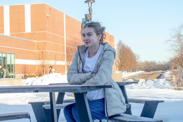 Smiling, News Editor-in-Chief Phoebe Morris sits at a picnic table.